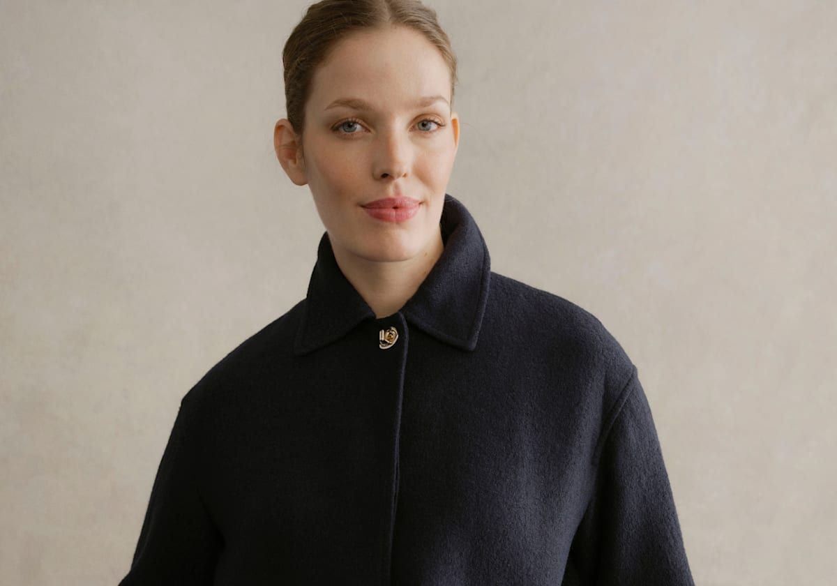 An image of a model wearing a navy wool coat, blue jeans and tan boots.