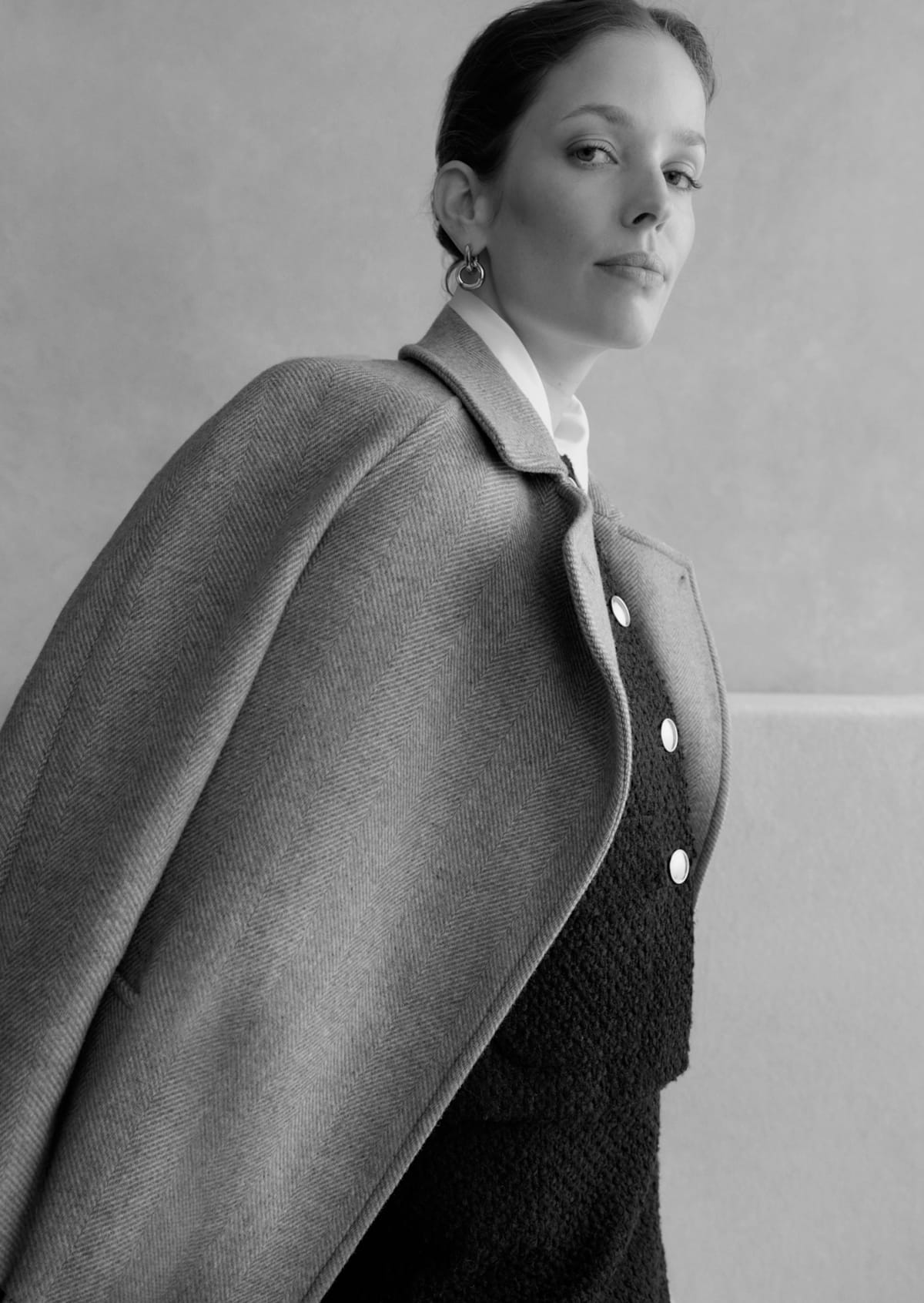 A gallery of two images displaying a model wearing a beige tailored coat.