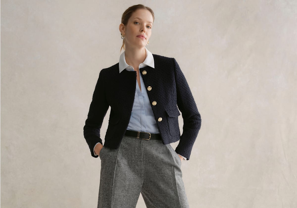 A gallery of three images displaying a model wearing a cropped navy jacket