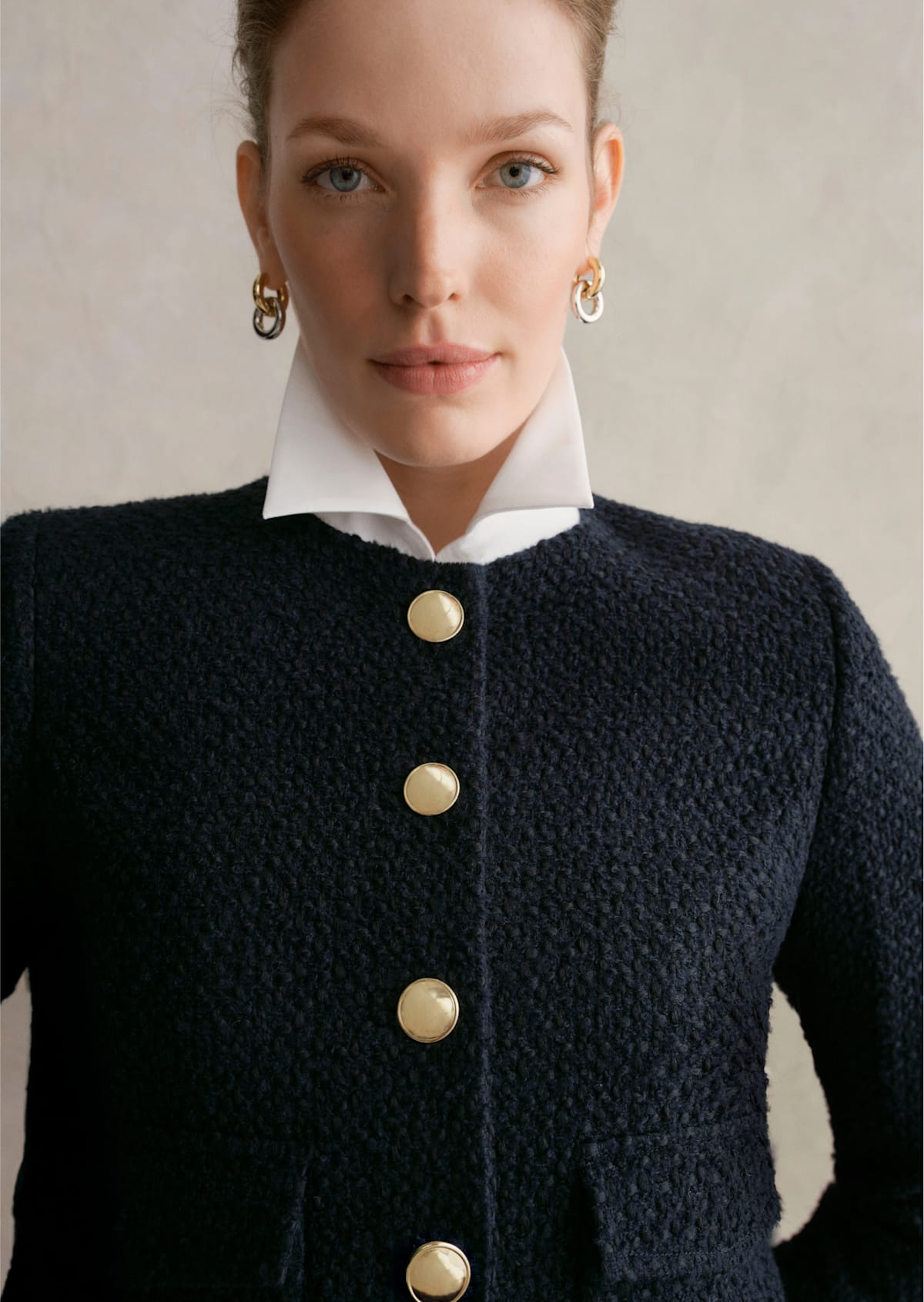 A gallery of three images displaying a model wearing a cropped navy jacket