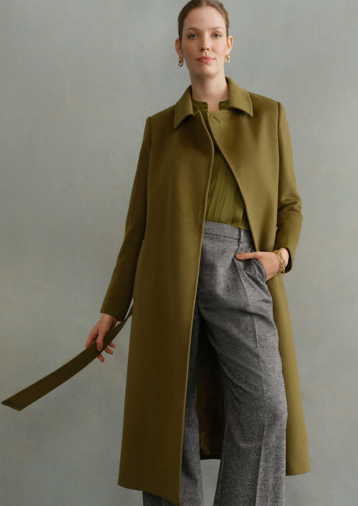 Image of a model wearing an olive green tailored coat over smartwear.