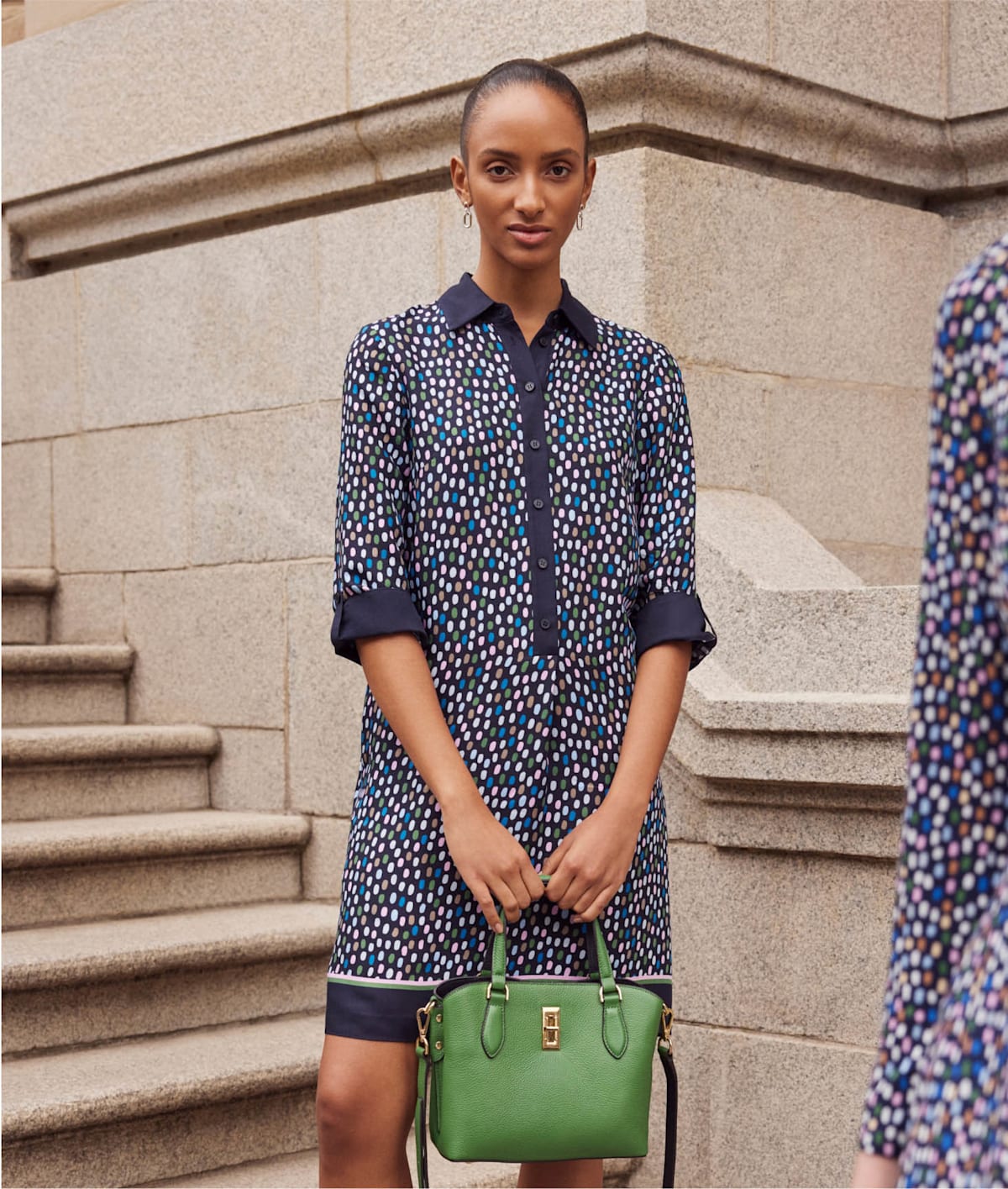 Photo of model outside building wearing a polka dot tunic dress.