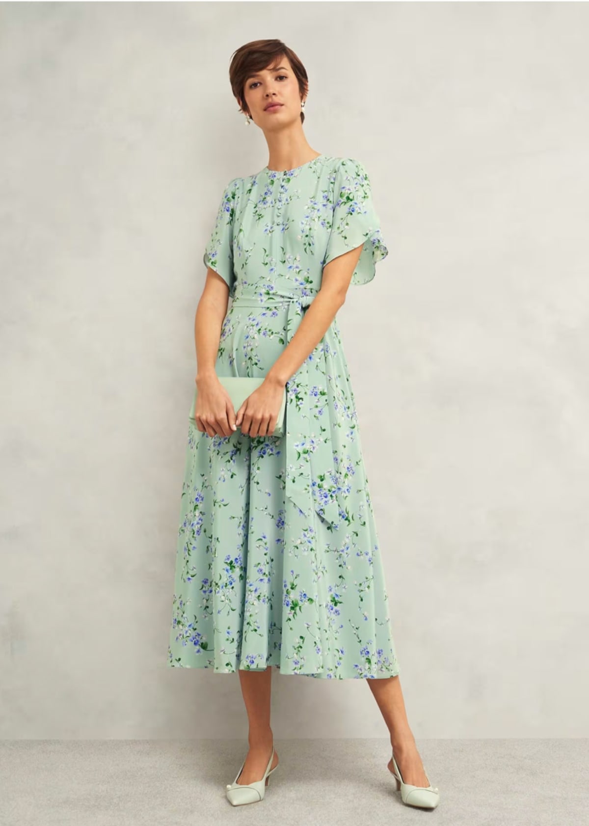 A gallery of four images of models wearing occasion floral midi dresses and coordinating accessories.