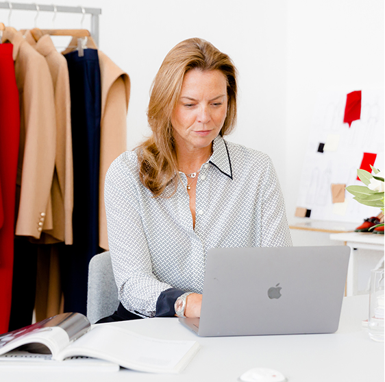 Hobbs' Product Director, Sally Ambrose, photographed wearing a silk shirt while working on her laptop.