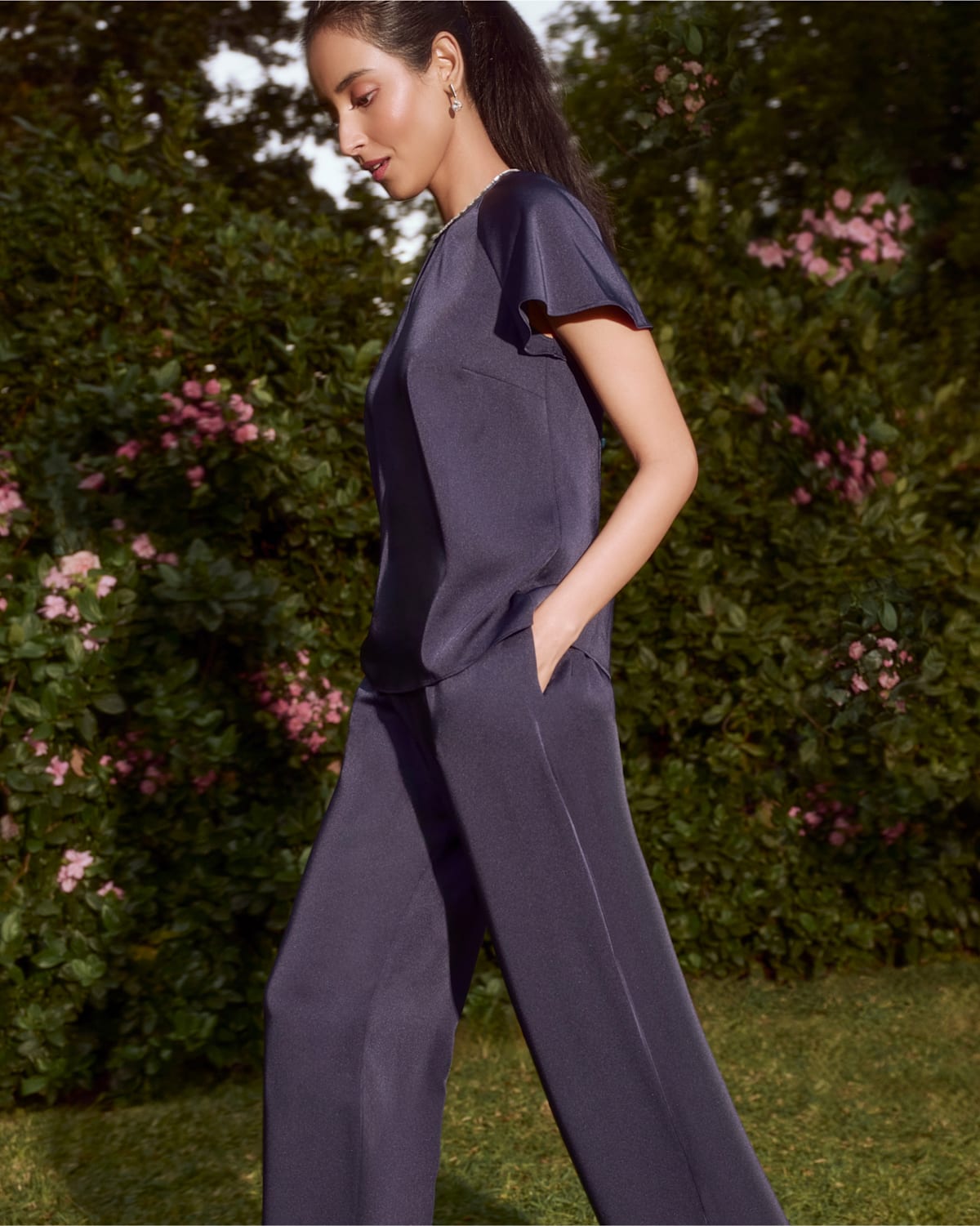 A collage of two images showing a model wearing a navy satin two piece.
