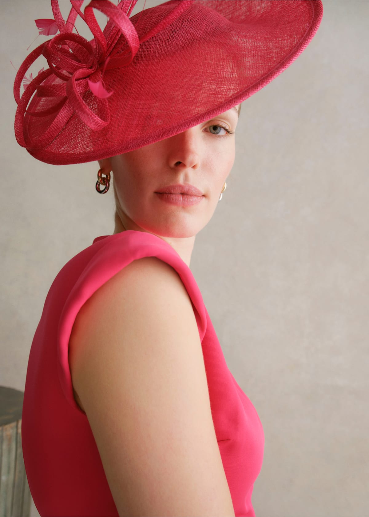 A gallery of two images displaying a model wearing a pink occasion dress with coordinating accessories.