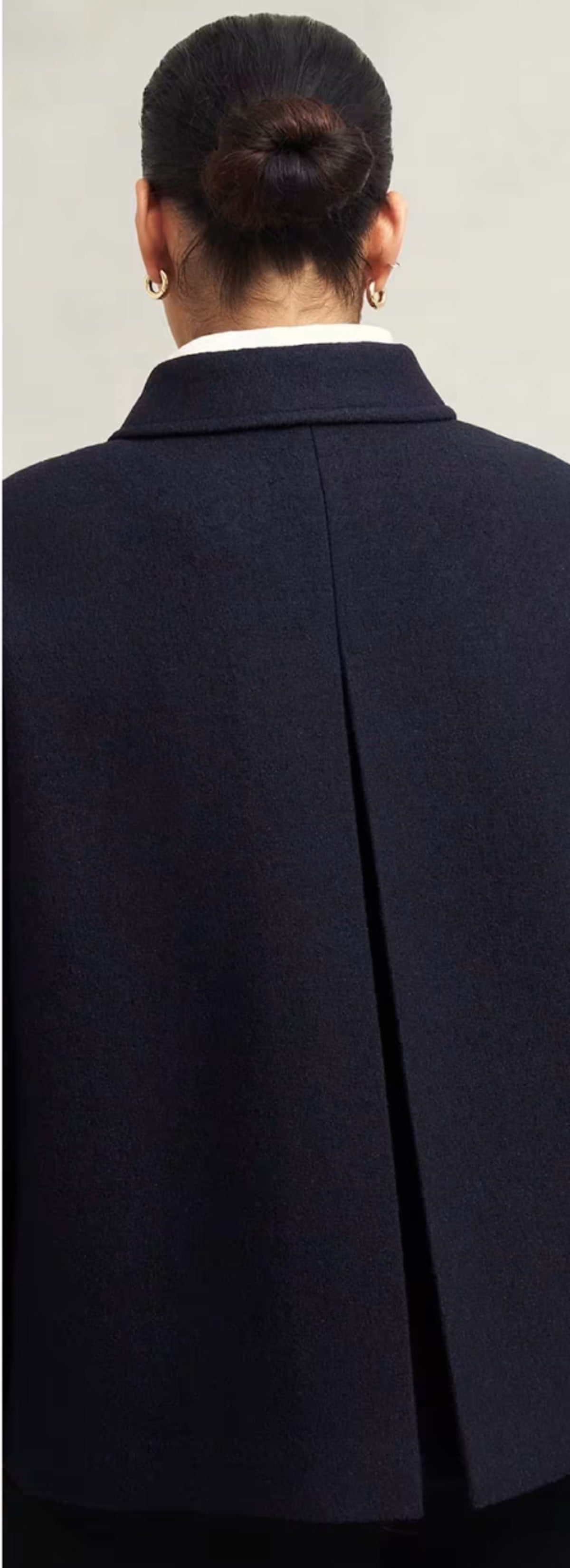 A gallery of four images including one image of a model wearing a navy coat, and three smaller images displaying details of the coat.