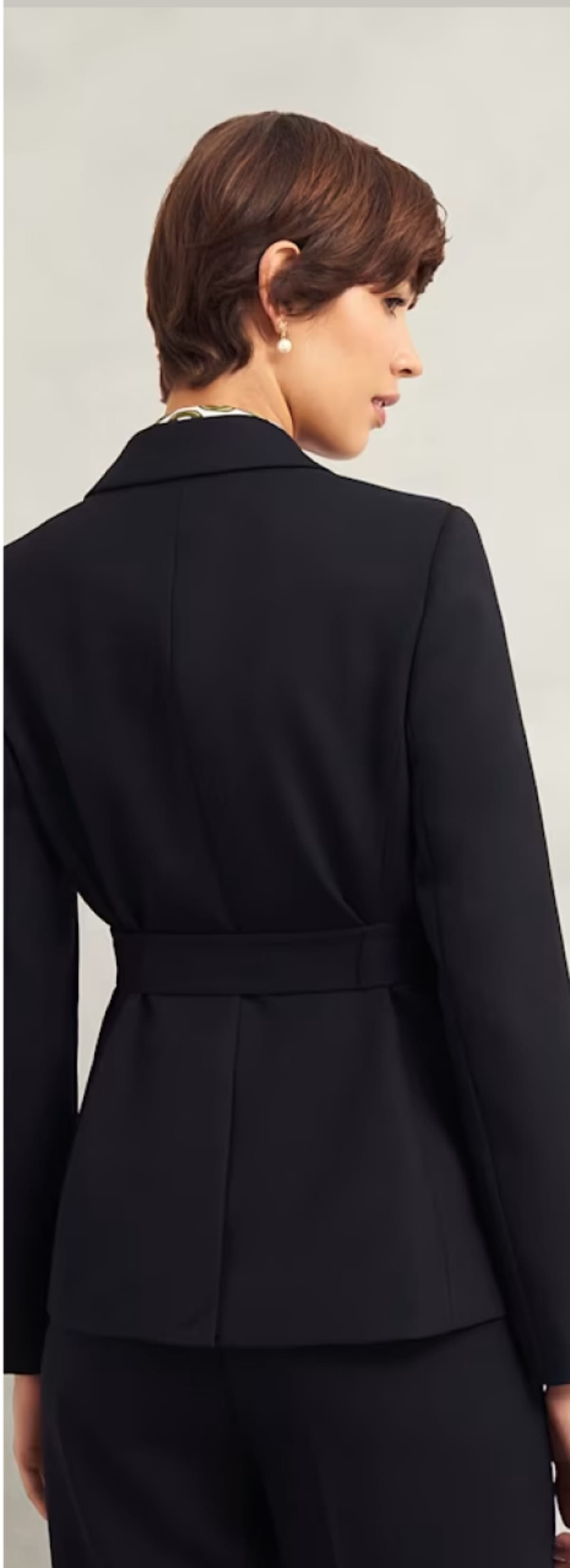A gallery of four images including one image of a model wearing a women’s black suit, and three smaller images displaying details of the blazer.